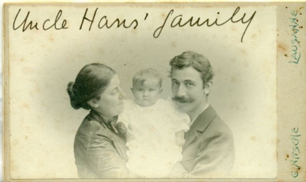 Ein altes Foto eines Mannes im Anzug und mit Krawatte, einer Frau mit einem Baby auf dem Arm und der Aufschrift "Onkel Hans' Familie" oben drauf, alle strahlend.