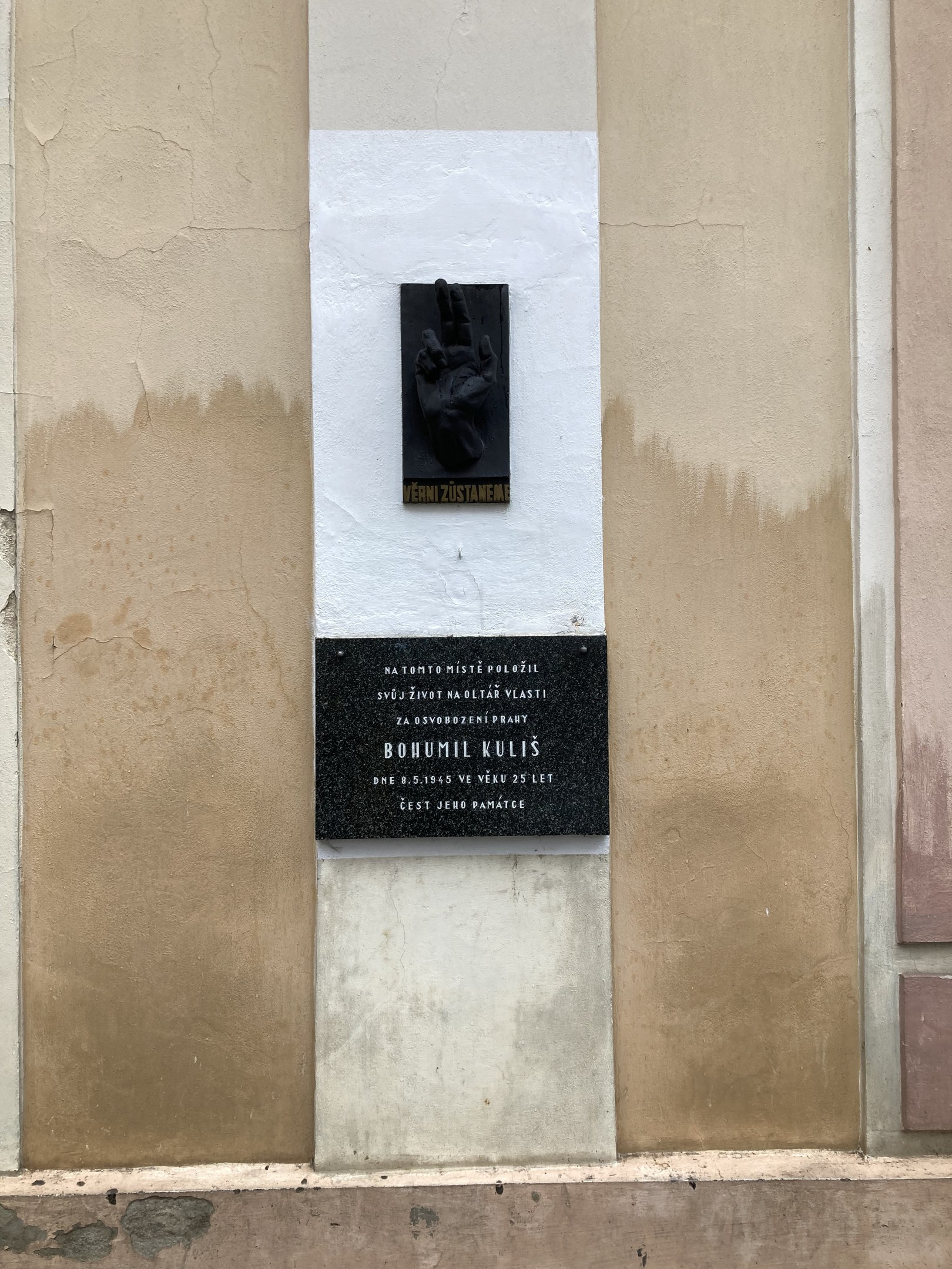 Schwarze Tafel an einem Gebäude mit einer Hand darauf, die mit Text beschriftet ist, der Holocaust-Opfer gedenkt.