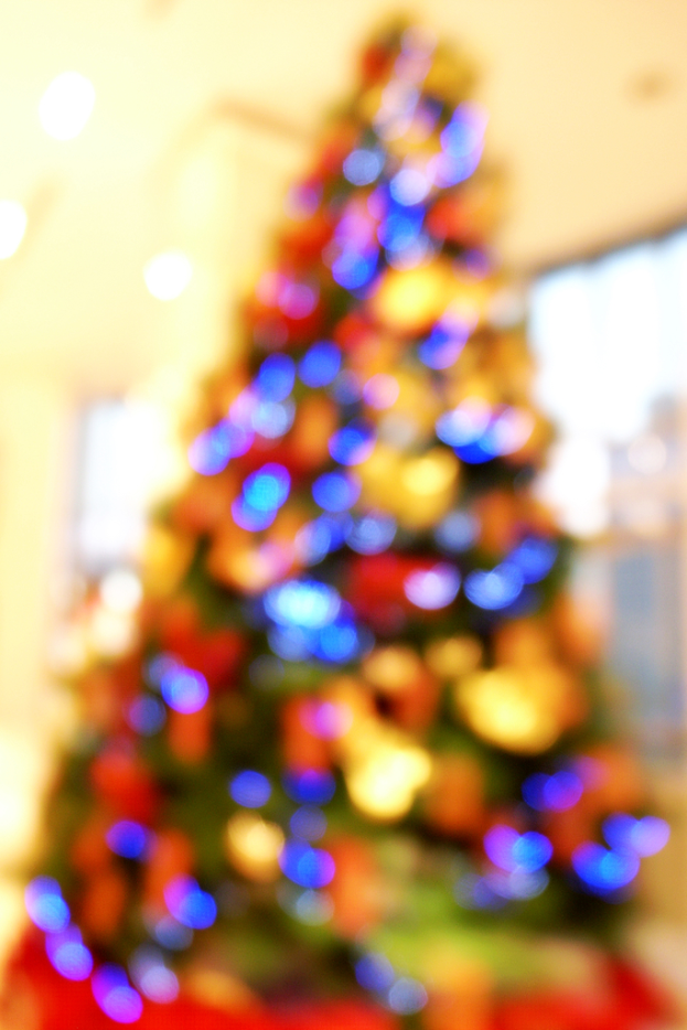 Ein unscharfer Innenraum mit einem Weihnachtsbaum, der mit Lichtern und Dekorationen geschmückt ist.