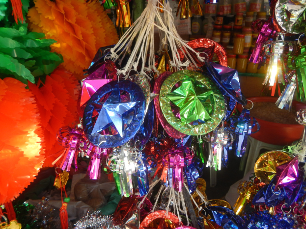 Farbenfrohe Dekorationen wie Laternen und Bänder hängen von der Decke über Regalen mit Flaschen in einer festlichen Atmosphäre.