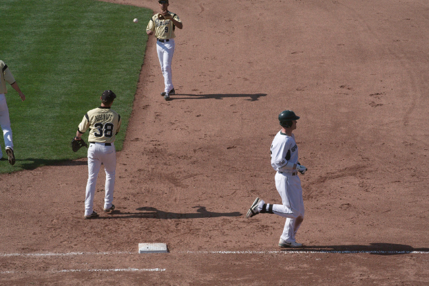 Ein Mann in weißem Kleid und schwarzer Mütze läuft rechts, während zwei Personen in gelben T-Shirts in der Mitte laufen, wahrscheinlich Cricket spielend.