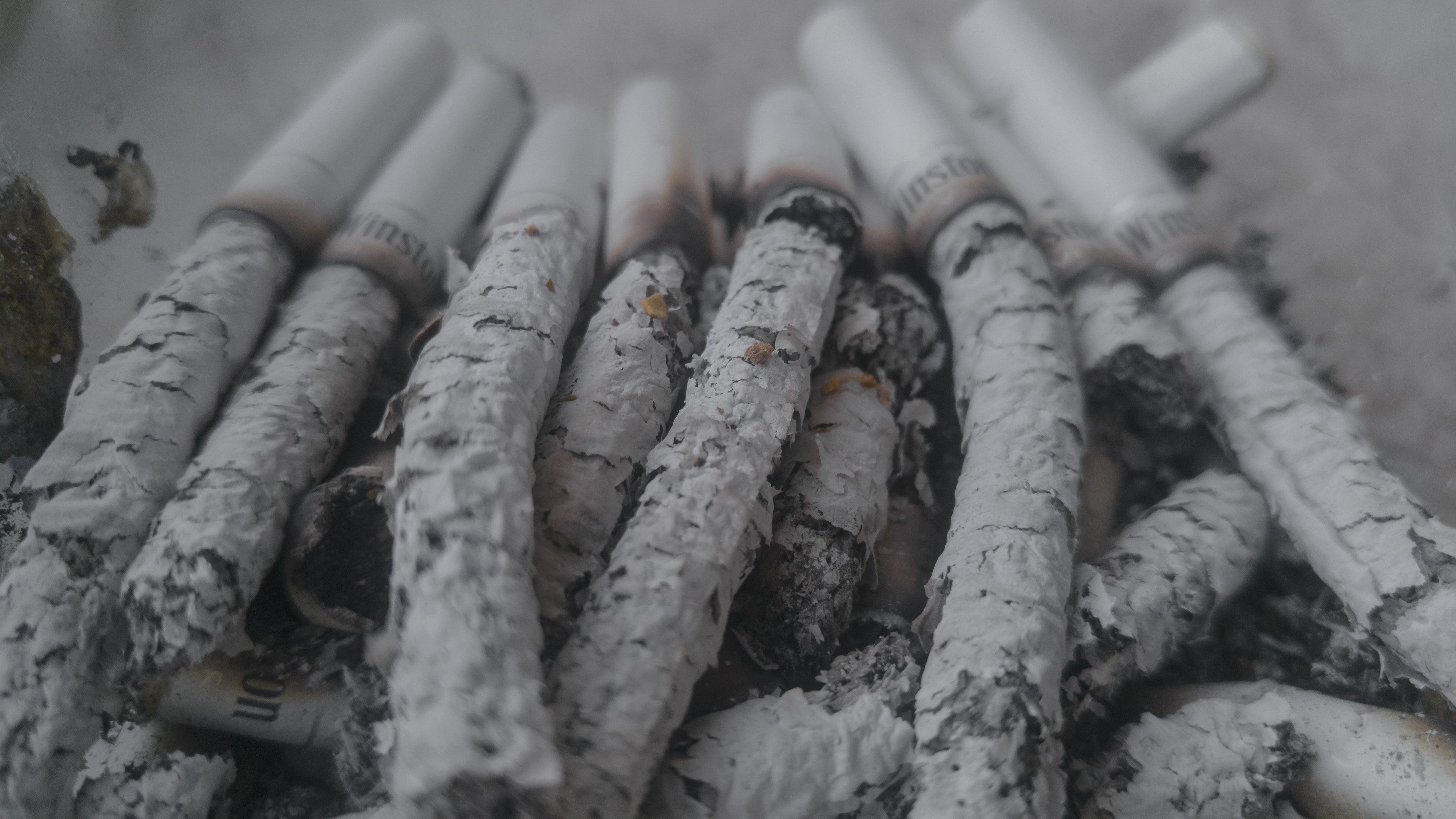 Ein unordentliches Häufchen aschfarbener Zigaretten auf einem Tisch.