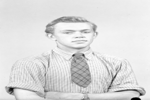 Ein Schwarz-Weiß-Foto eines Mannes, der ein Hemd, eine Krawatte und eine Uhr am Handgelenk trägt.