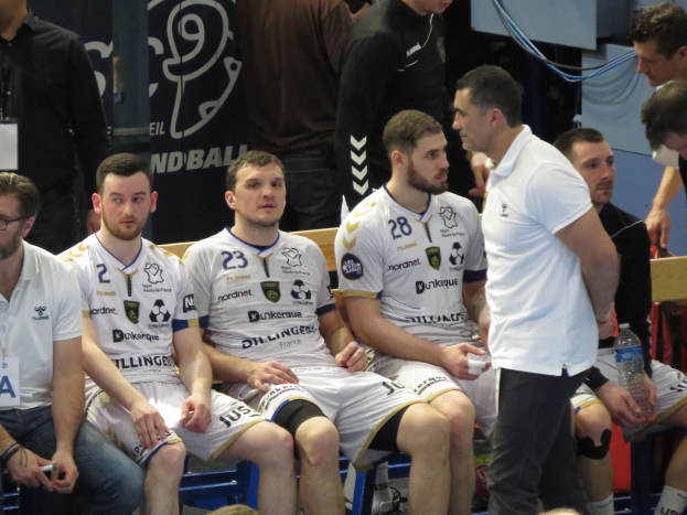 Eine Gruppe von Männern sitzt auf einer Bank, einige halten Flaschen, im Hintergrund ein Banner mit der Aufschrift "Nordkraque vs Bordeaux."