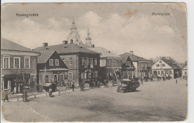 Schwarz-weiß-Fotografie einer Stadtstraße in Nowogrodziec, Deutschland, mit Gebäuden, Menschen, Karren, Pfählen, Bäumen und Himmel, mit dem Text "Marktplatz in Nowogrodeek, Deutschland" oben und unten.