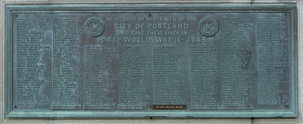 Metallplatte an einer Gebäudewand angebracht mit der Aufschrift "Denkmal für die Stadt Portland" in fetter schwarzer Schrift, eingerahmt von einem dekorativen Rand.