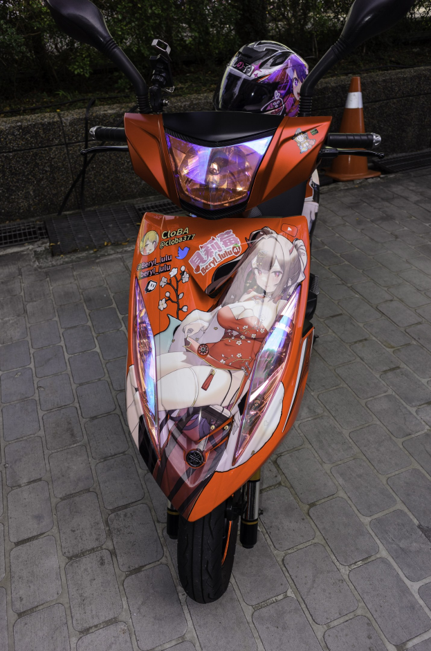 Ein oranges E-Scooter mit einem Helm darauf neben einem Verkehrskegel, einer Wand und Bäumen im Hintergrund.