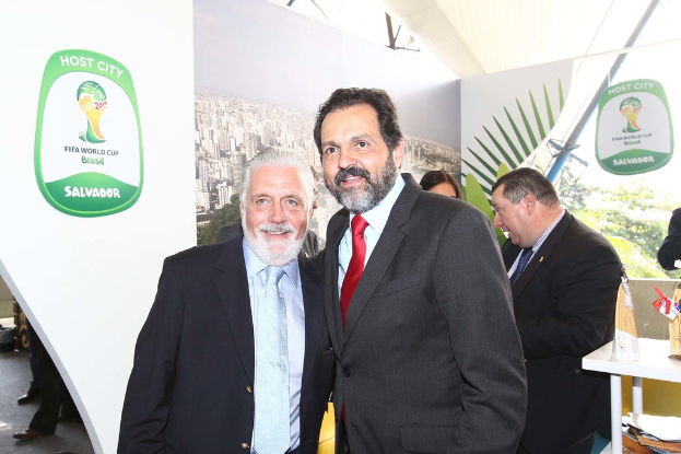 Eine Gruppe von Menschen, die mit einigen, die lächeln, und einem FIFA-WM-Poster im Hintergrund stehen.