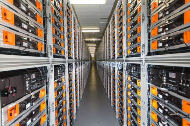 Eine lange Reihe von Servern in einem Rechenzentrum mit elektronischen Geräten in den Racks und Leuchten oben.