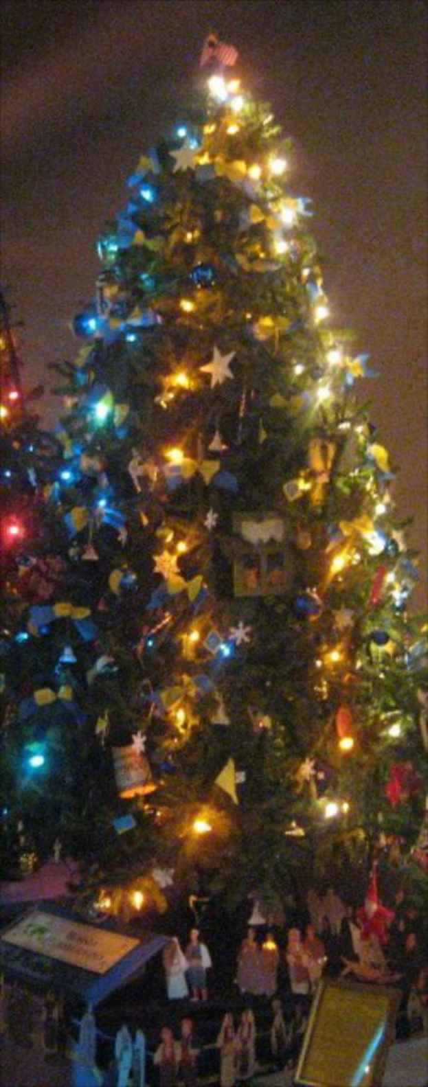 Ein geschmückter Weihnachtsbaum mit Menschenfiguren auf einem darunter platzierten Tisch.