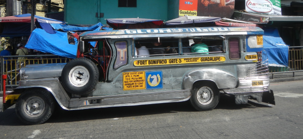 Ein Jeepney ist auf der Seite der Stra├če vor einem Geb├Ąude geparkt, mit Menschen, die darin sitzen, und verschiedenen Gegenst├Ąnden, darunter Zelte, Gel├Ąnder, St├Ąbe und Bretter mit Text und Bildern im Hintergrund.
