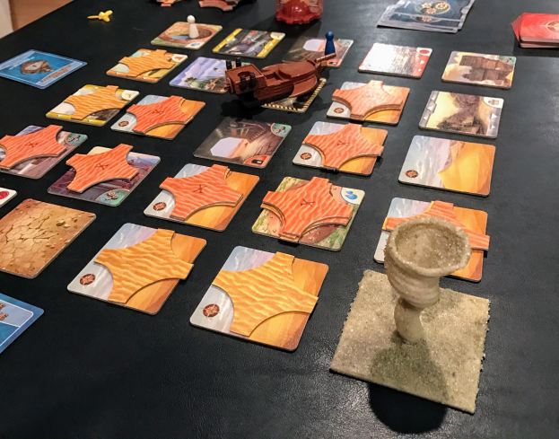 Ein unordentlicher Tisch mit Star Wars: The Old Republic-Spielkarten, Spielzeugen und Gegenständen in einem Raum mit sichtbarer Wand.