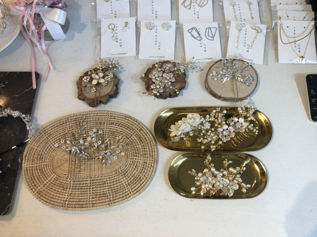 Ein unordentlicher Brautladen-Tisch mit verschiedenen Schmuckstücken, Papieren, einer Tastatur und einem Mobiltelefon sowie anderen Gegenständen.