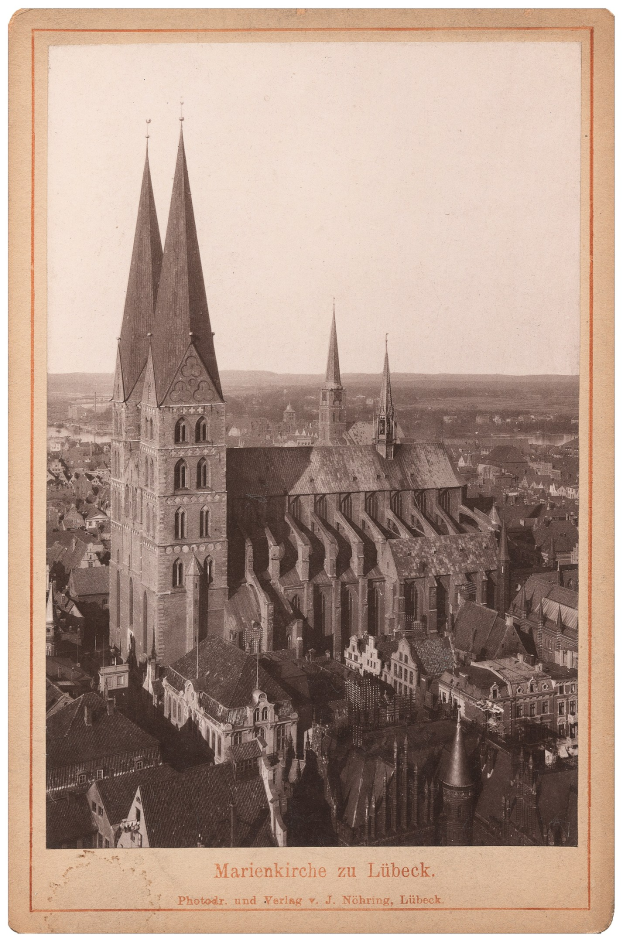 Altes Schwarz-Weiß-Foto einer Stadt mit einer prominenten Kirche in der Mitte, umgeben von verschiedenen Gebäuden, mit Text unten.