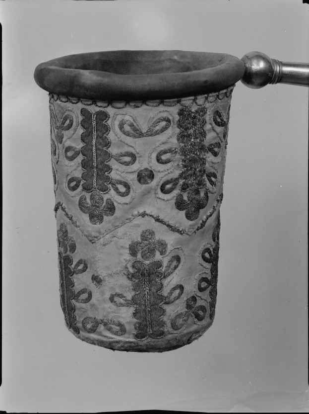 Ein Schwarz-Weiß-Foto eines Stoff-Müllpapierkorbs mit Griff.