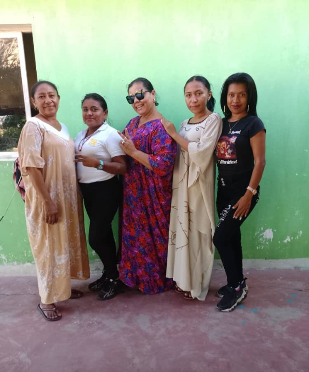 Eine Gruppe von Frauen, die vor einer grünen Wand mit einem Fenster auf der linken Seite steht und an einem Internationalen Frauentag-Event teilnimmt.