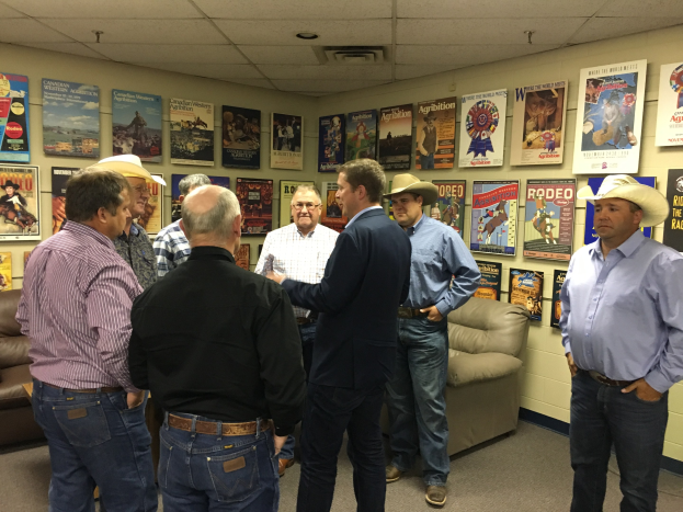 Eine Gruppe von Männern steht in einem Raum mit Sofas, Postern an den Wänden und Deckenleuchten und ist in ein Gespräch vertieft.