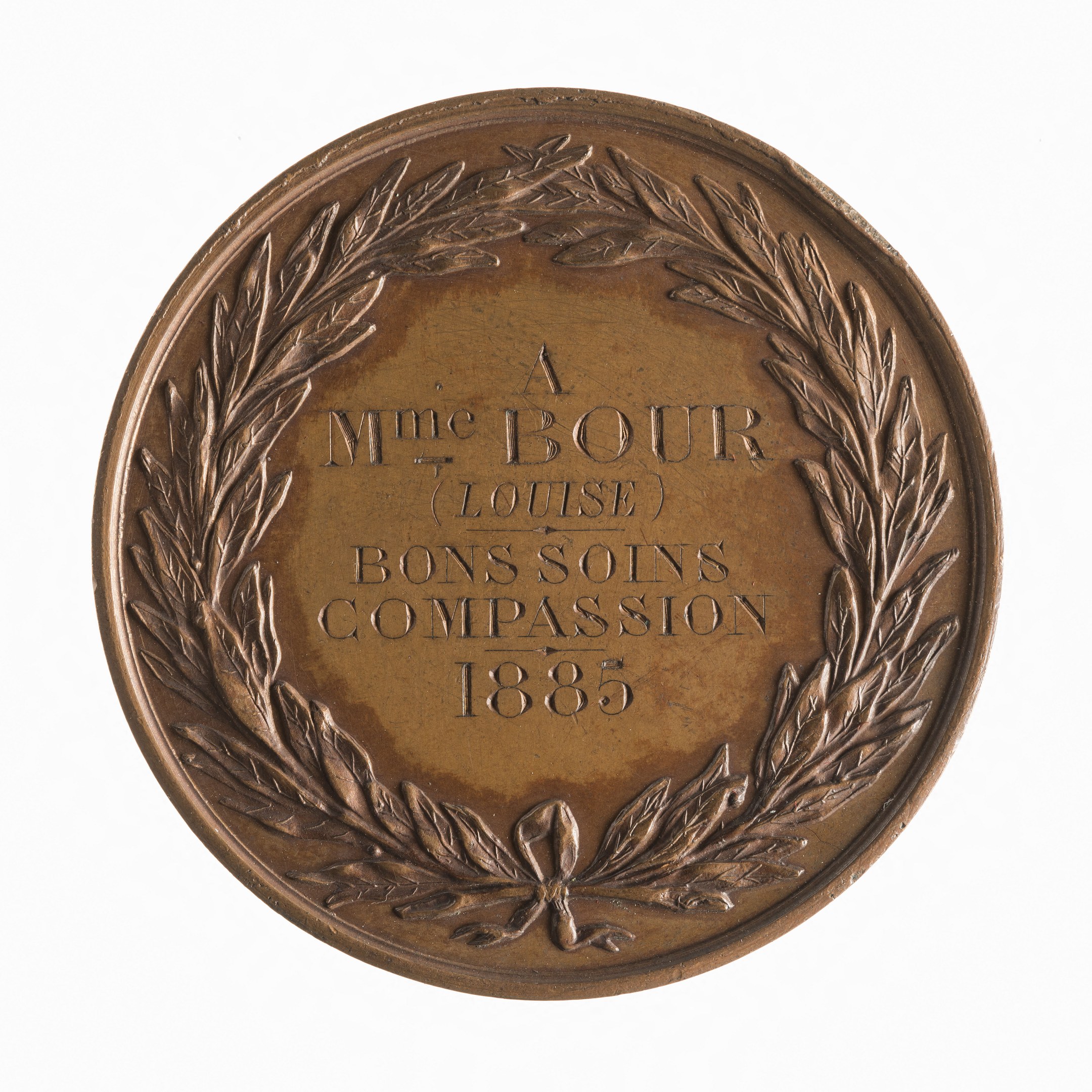 Bronze-Medaille mit Lorbeerkranz und der Aufschrift "Bons Soins Compassion" vor weißem Hintergrund.
