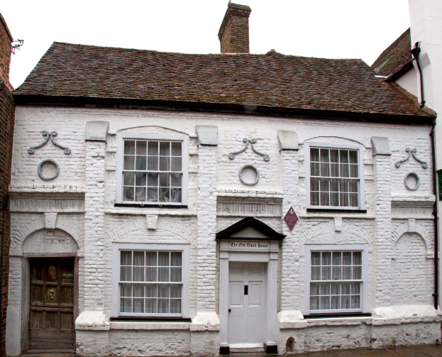 Ein weißes Haus mit einem braunen Ziegeldach und einem Schornstein.