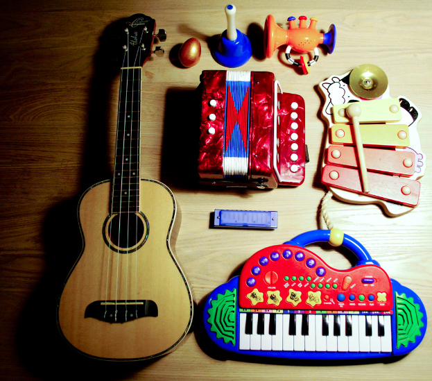 Ein Tisch mit einer Gitarre, Xylophon, Harmonikas, einem musikalischen Piano, einem Spielzeug, einem Plastikei und einem Horn.