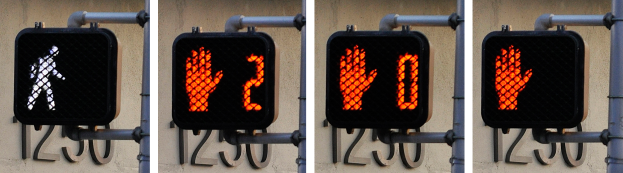 Eine Ampel an einem Gebäude angebracht, die drei verschiedene Arten von Verkehrssignalen anzeigt.