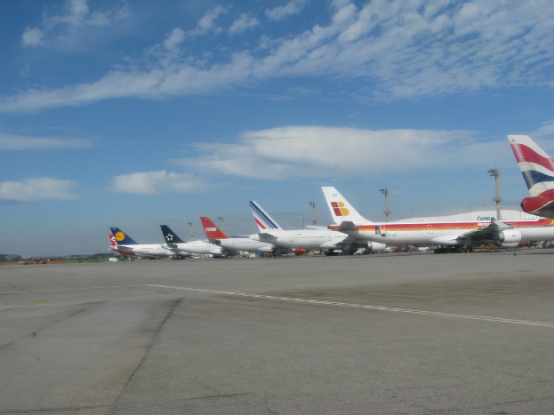Eine Start- und Landebahn mit einigen Flugzeugen, Polen, Kabeln und ein paar Wolken am Himmel.