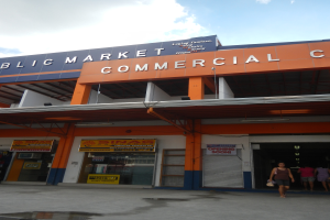 Ein öffentliches Marktzentrum mit Menschen davor, mit Text an dem Gebäude und einem sichtbaren Himmel oben.