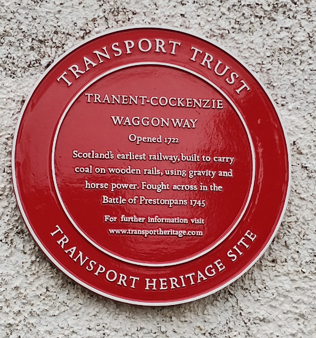 Ein rundes rotes Schild an einem Gebäude mit der Aufschrift "Transport Trust"