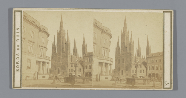 Altes Schwarz-Weiß-Foto einer Stadtstraße mit mehrstöckigen Gebäuden, Pferdewagen, Fußgängern, Straßenlaternen, Versorgungsmasten und Bäumen am Straßenrand.