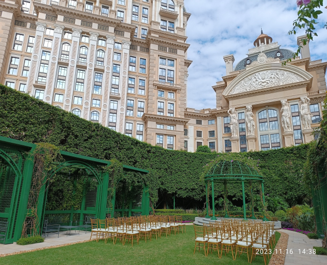 Freiluft-Hochzeit mit Stühlen, Pavillon und Grün unter einem klaren blauen Himmel.