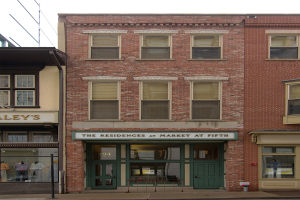 Verkaufsfläche von "Residences at Market at Fifth" mit Glasfenstern und -türen, Schaufensterpuppen in Kleidern, einer Straße und Himmel.
