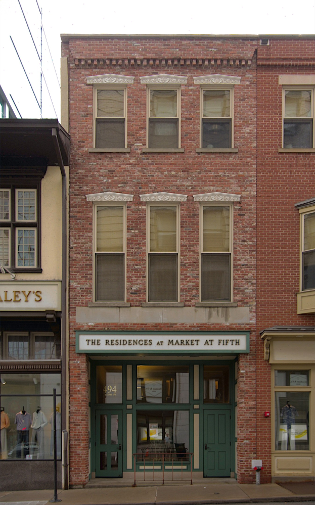 Verkaufsfläche von "Residences at Market at Fifth" mit Glasfenstern und -türen, Schaufensterpuppen in Kleidern, einer Straße und Himmel.