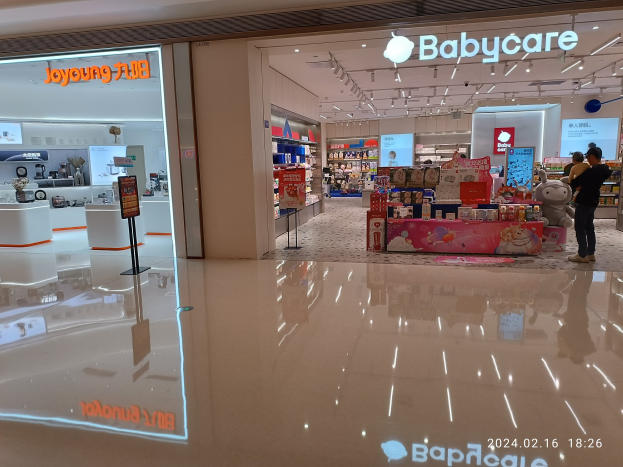 Babybedarfsladen im Mall of Asia mit Menschen, die Spielzeug und Artikel auf Regalen unter Deckenleuchten durchstöbern.