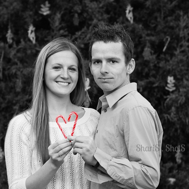 Ein Mann und eine Frau im Freien mit zwei Strohhalmen, im Hintergrund ein Weihnachtsbaum.