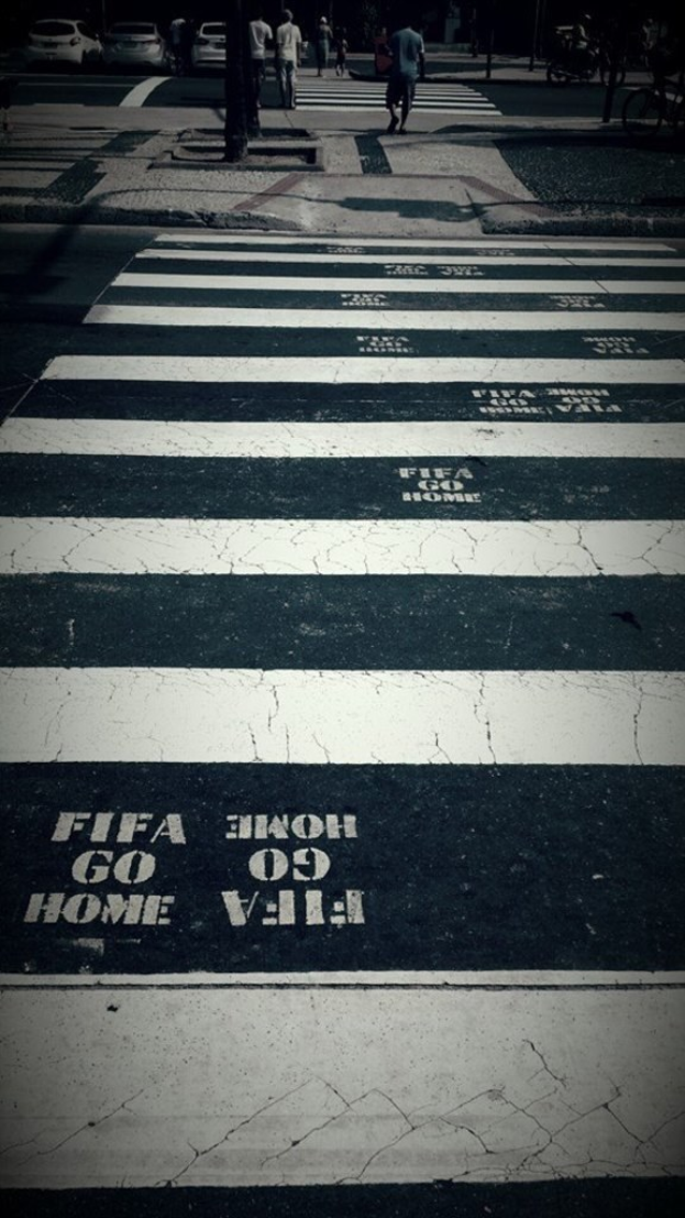 Menschen auf einem Zebrastreifen mit sichtbaren Autos im oberen linken Eck.