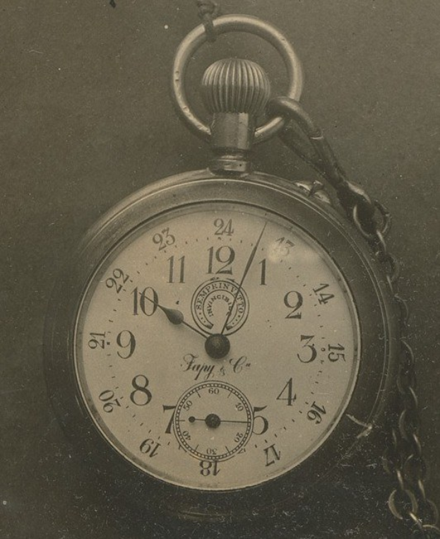 Alte Schwarz-Weiß-Fotografie einer Taschenuhr mit einer Kette, die eine nummerierte Uhr zeigt.