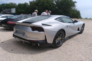 Ferrari 812 Superfast beim Goodwood Festival of Speed, umgeben von Menschen mit Mützen, mit Bäumen und Informationsschildern im Hintergrund unter einem bewölkten Himmel.